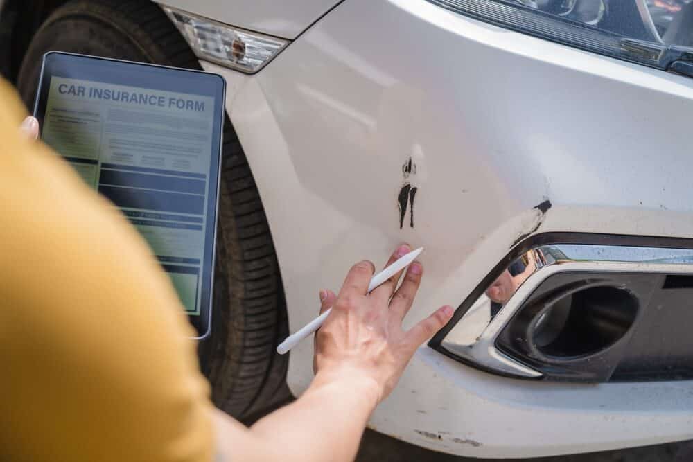 Man fills out a car insurance form after a car accident.