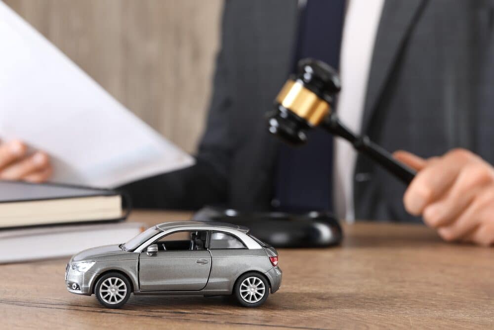 Auto accident law. Man with document and gavel at wooden table indoors, focus on toy car.