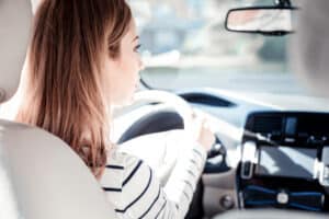 I see everything. Careful young cute woman sitting in her car holding by the helm looking on the road.