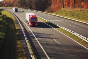 A truck with semi-truck drives through a wide landscape.