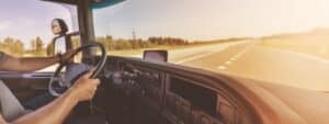 Truck driver sitting behind the wheel and driving a vehicle.