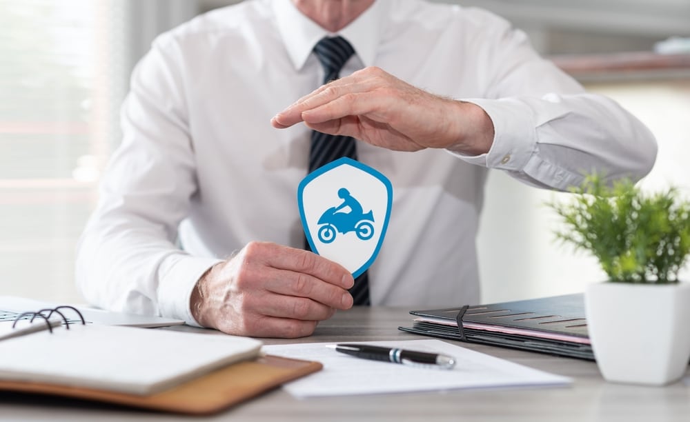 Concept of motorbike insurance with paper shield protected by hand of insurer
