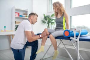 Mature patient completing rehabilitation with a physiotherapist after experiencing pain and suffering from an injury