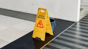 Yellow sign reading “Caution Wet Floor” that has been displayed in a parking garage as a way to comply with Arizona’s slip and fall laws.