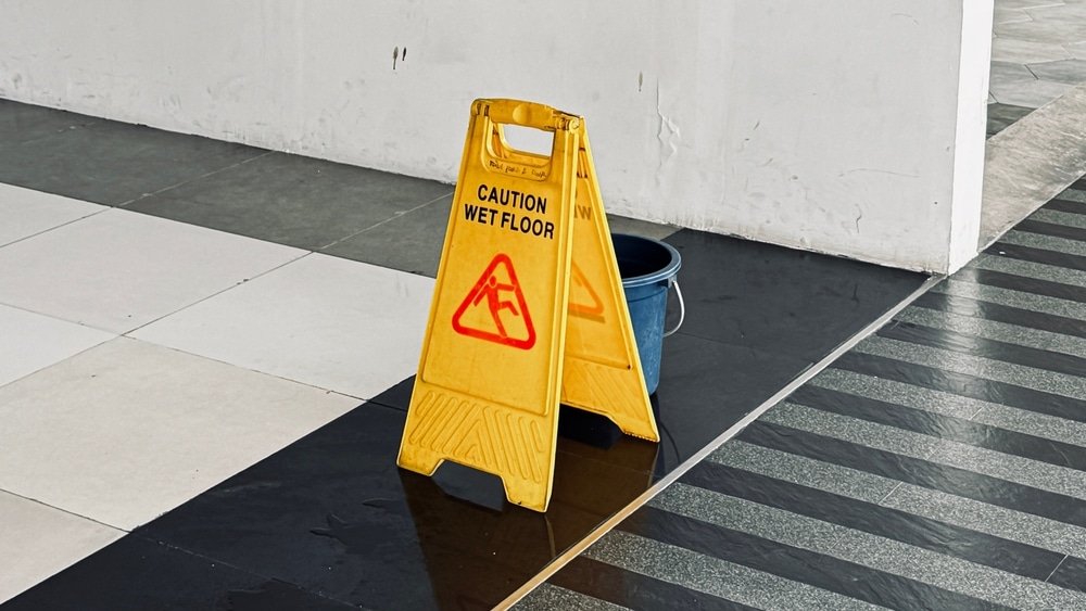 Yellow sign reading “Caution Wet Floor” that has been displayed in a parking garage as a way to comply with Arizona’s slip and fall laws.