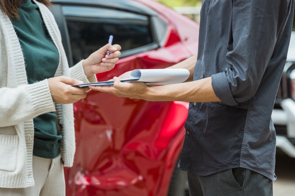 A client signing forms after a car accident. Learn about the car accident settlement process in California.
